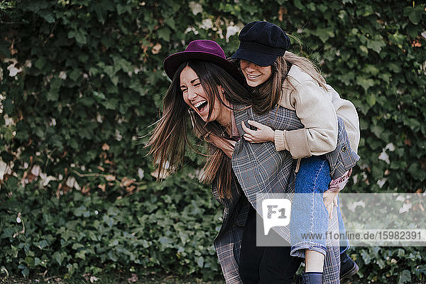 Laughing woman giving her friend a piggyback ride