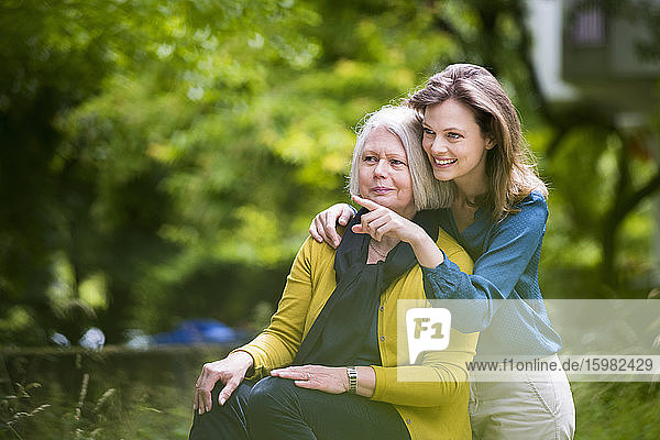 Porträt einer älteren Frau und ihrer erwachsenen Tochter  die in einem Park etwas beobachten