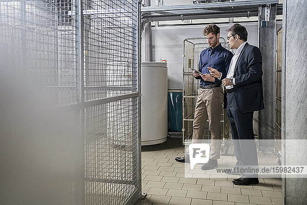 Two businessmen with tablet having a meeting in a factory
