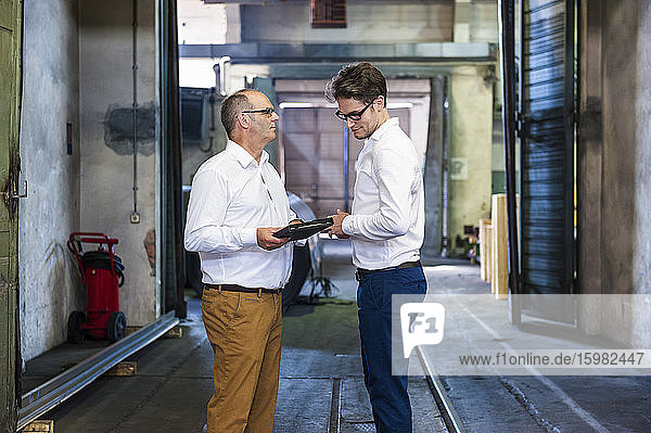 Two businessmen having a meeting in a factory hall