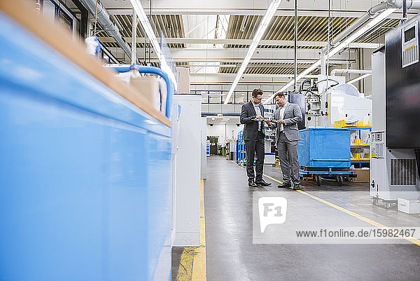 Two businessmen examining a product in a factory