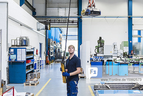 Man working with indoor crane in a factory