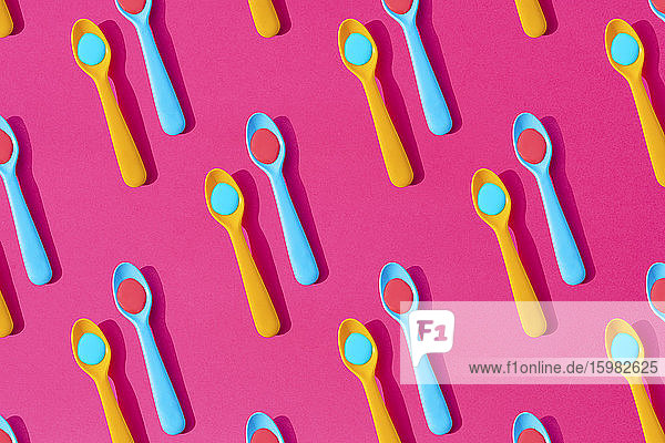 Seamless pattern of yellow and blue plastic teaspoons with blue and red liquid