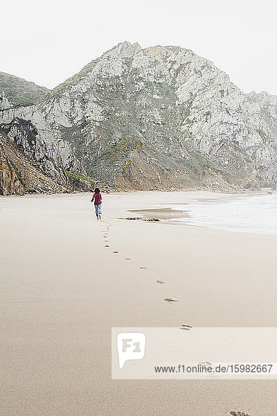 Frau hinterlässt Fußspuren beim Laufen am Strand von Ursa  Region Lisboa  Portugal