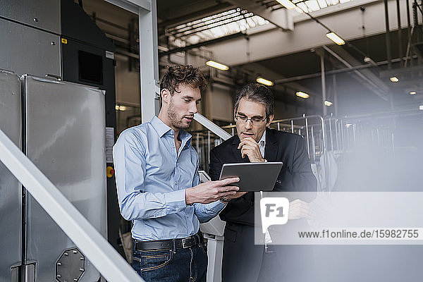Two businessmen with tablet having a meeting in a factory