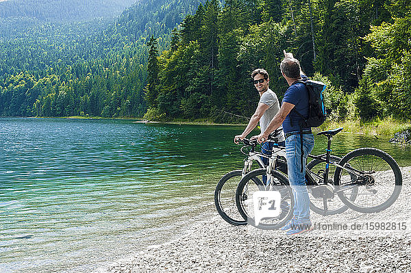 Senior and mature man with e-bikes at Eibsee lakeside