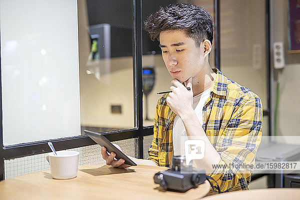 Porträt eines jungen Touristen  der in einer Herberge sein Smartphone benutzt
