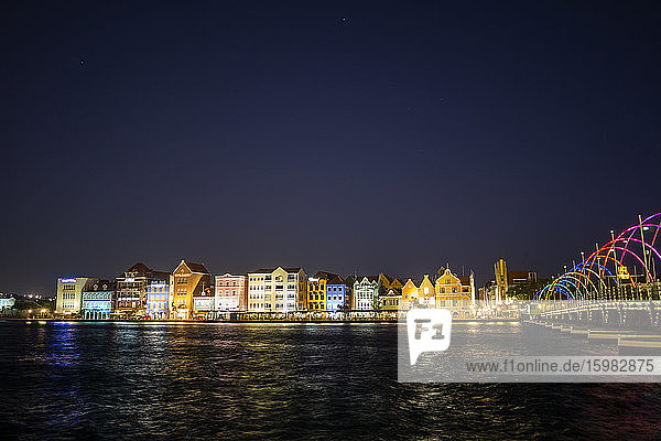Illuminated buildings by sea against clear sky at night in Willemstad  Curacao