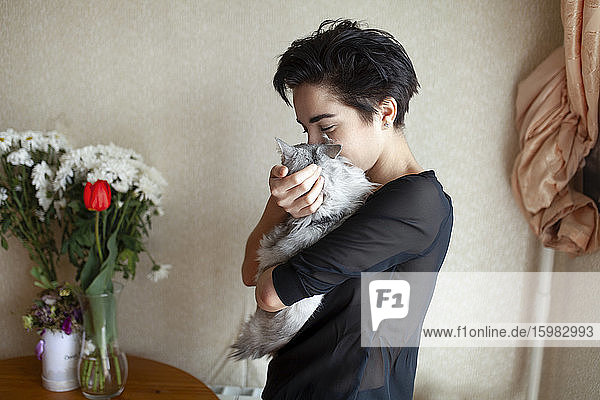 Frau kuschelt Katze zu Hause