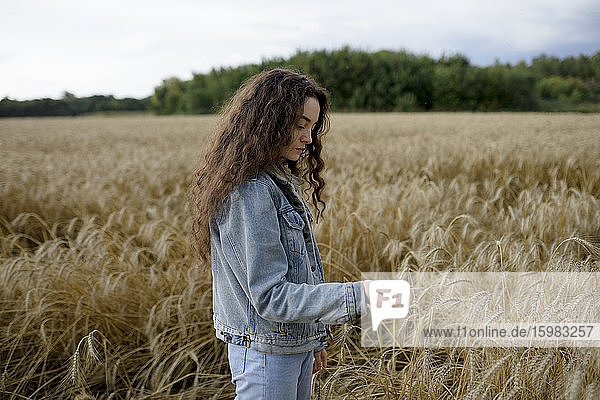 Russland  Omsk  Junge Frau steht im Weizenfeld