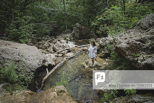 Ukraine  Crimea  Young woman standing on rock in river