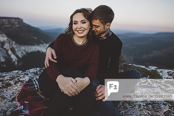 Ukraine  Krim  Junges Paar sitzt und umarmt sich am Canyon
