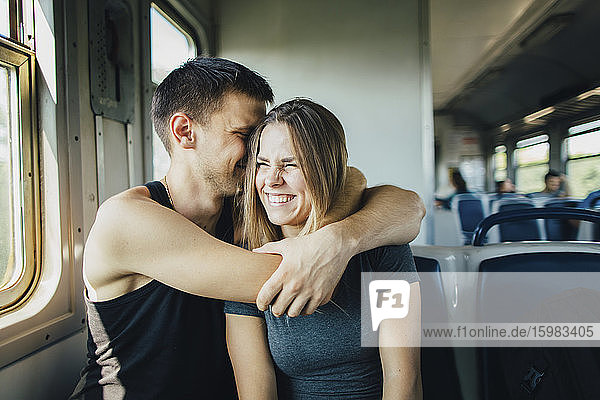 Junges Paar umarmt sich im Zug