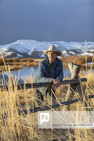 USA  Idaho  Sun Valley  Älterer Mann lehnt am Zaun und schaut auf die Aussicht