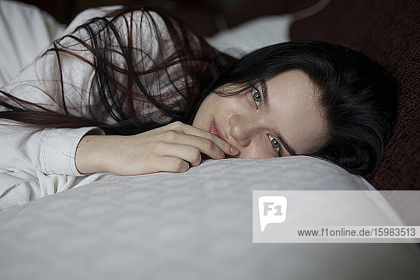 Porträt einer auf dem Bett liegenden jungen Frau