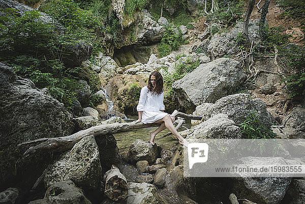 Ukraine  Crimea  Young woman sitting on branch over river in canyon
