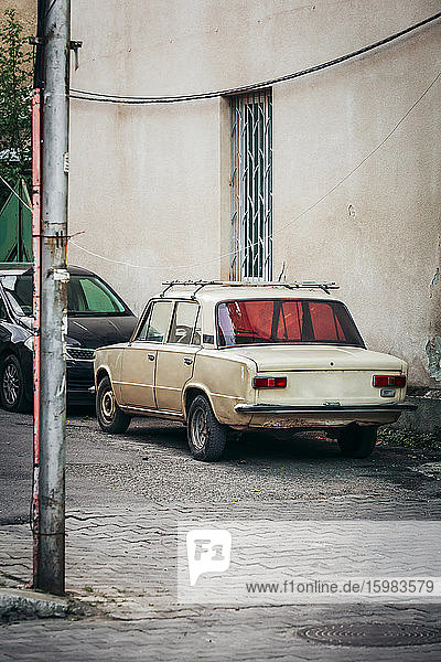 Georgien  Imereti  Kutaisi  Autos am alten Gebäude geparkt