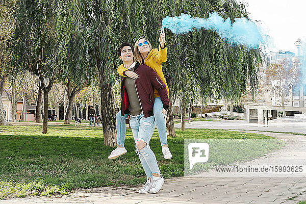 Glücklicher junger Mann mit Freundin und Rauchfackel im Park