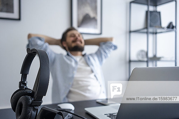 Man leaning back at desk  focus on headphone
