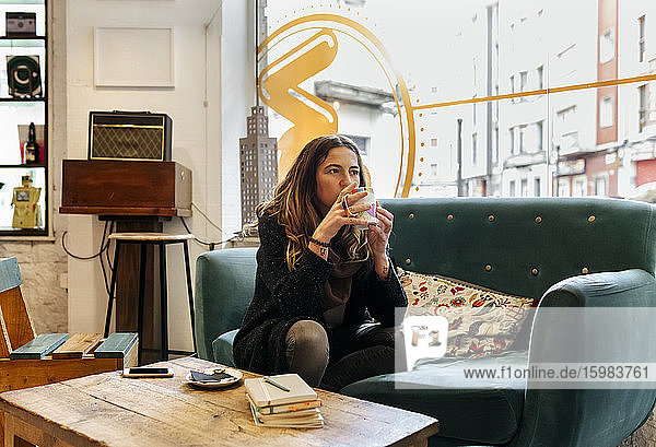 Frau trinkt Kaffee auf der Couch in einem Café