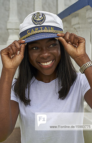 Porträt einer glücklichen jungen Frau mit Kapitänsmütze