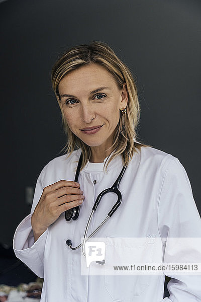 Porträt eines Arztes mit Stethoskop vor grauem Hintergrund