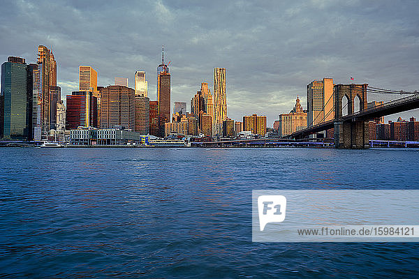 USA  New York  New York City  East River und Brooklyn Bridge in der Morgendämmerung mit der Skyline von Manhattan im Hintergrund