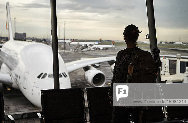 Südafrika  Johannesburg  Rückansicht einer Frau  die vom Flughafenterminal aus die Flugzeuge auf dem Rollfeld betrachtet