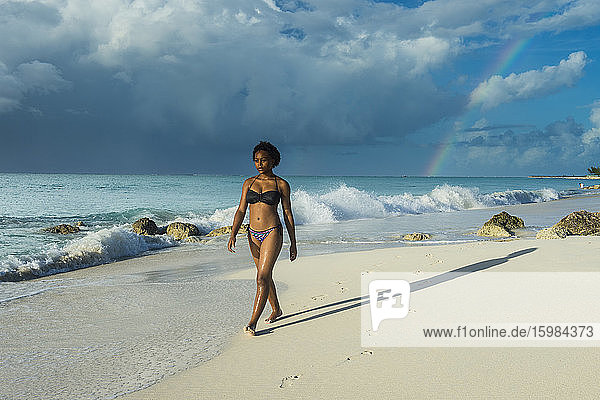 Frau im Bikini spaziert am Strand von Grace Bay gegen bewölkten Himmel  Providenciales  Turks- und Caicosinseln