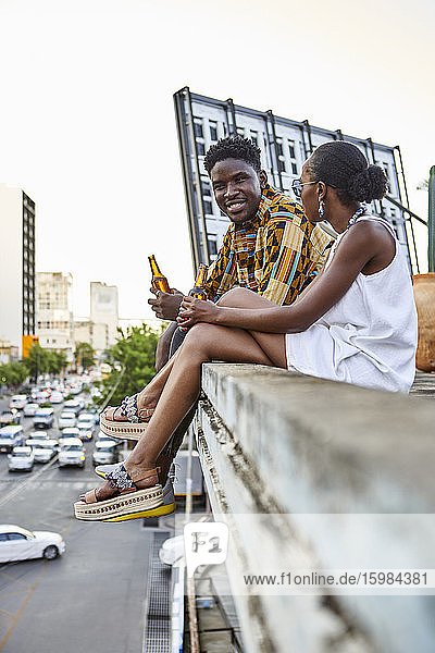 Paar sitzt auf einer Dachterrasse in der Stadt und trinkt Bier  Maputo  Mosambik