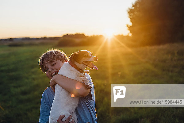 Playful boy with dog on field during sunset  Poland