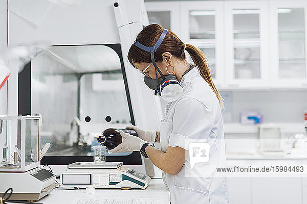 Arzt gießt eine Chemikalie in ein Becherglas auf einer Waage  während er im Labor forscht