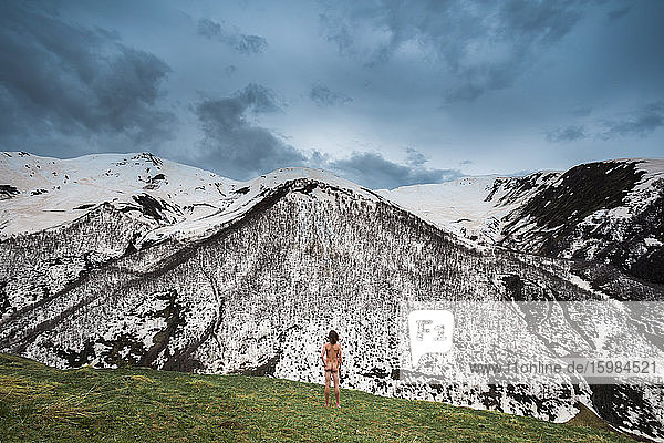 Georgien  Swanetien  Ushguli  Männlicher Nudist bewundert schneebedeckte Gipfel im Kaukasusgebirge
