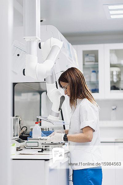 Mature female scientist using equipment while working at desk in laboratory