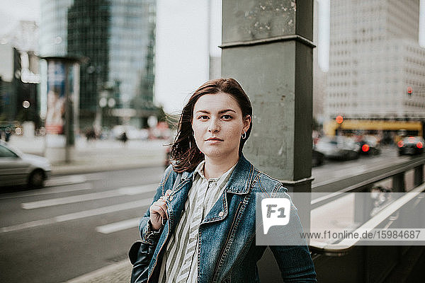 Deutschland  Berlin  Porträt einer jungen Frau auf dem Bürgersteig