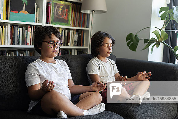 Siblings sitting on couch meditating
