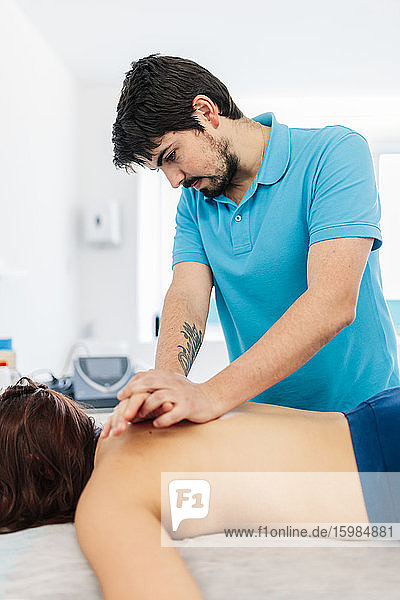 Ein sehbehinderter männlicher Therapeut massiert einer Frau in einer Klinik den Rücken