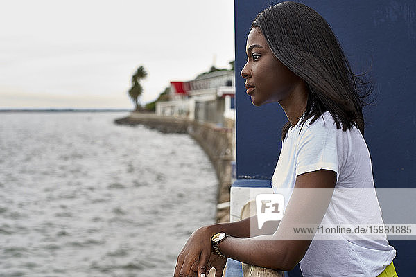 Profil einer jungen Frau auf einer Terrasse mit Blick auf das Meer