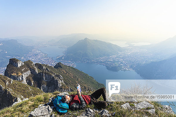 Rückansicht eines Wanderers  der auf einem Berggipfel ein Buch liest  Orobie-Alpen  Lecco  Italien