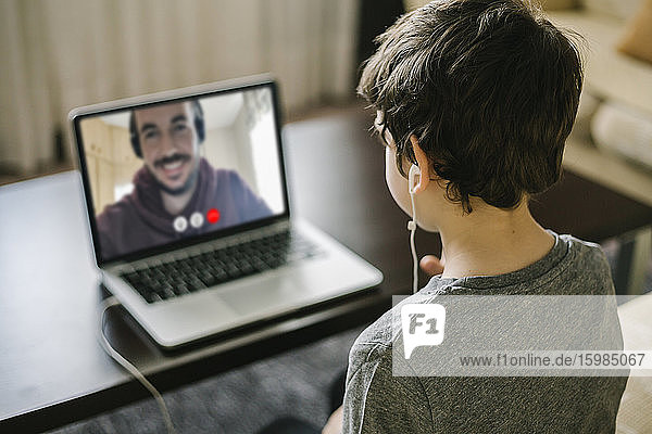 Kleiner Junge benutzt einen Laptop für einen Videochat mit seinem Vater