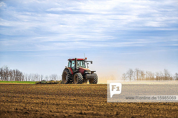 Landwirt im Traktor pflügt Feld im Frühling