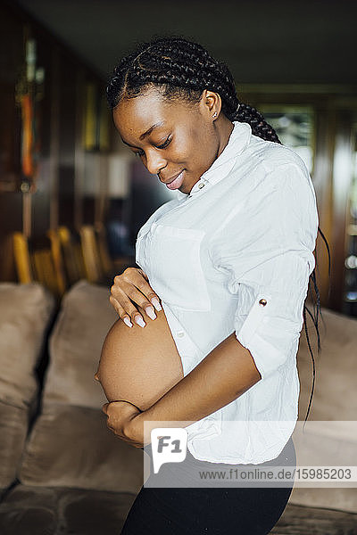Porträt einer schwangeren jungen Frau  die ihren Bauch berührt