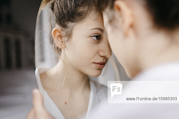 Close-up of young woman looking at mirror reflection