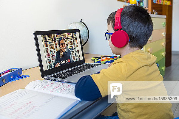 Junge hört Lehrer über Kopfhörer bei Videoanruf zu Hause zu