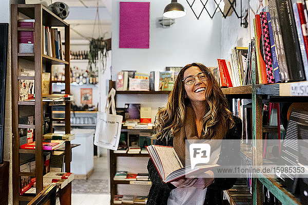 Lachende Frau  die in einem Café ein Buch liest