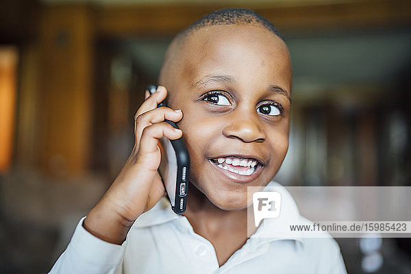 Porträt eines glücklichen kleinen Jungen am Telefon