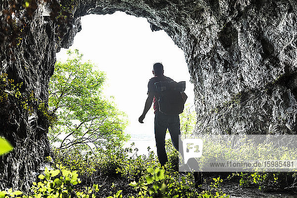 Mature man exploring while walking amidst plants in cave