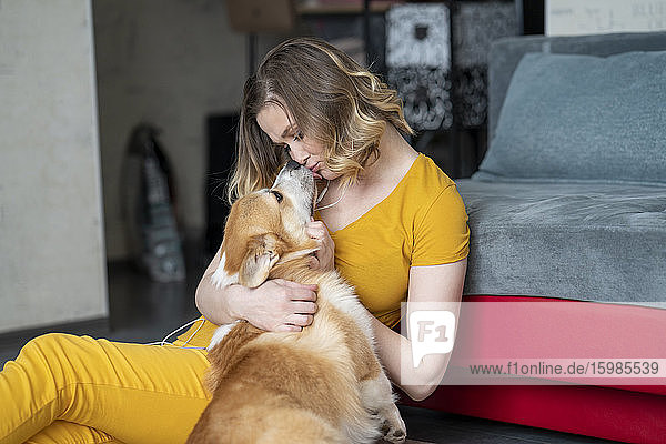 Frau kuschelt mit ihrem Hund im heimischen Wohnzimmer
