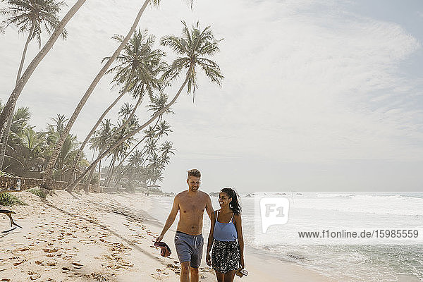 Happy couple walking together at beach while enjoying vacations in Sri Lanka
