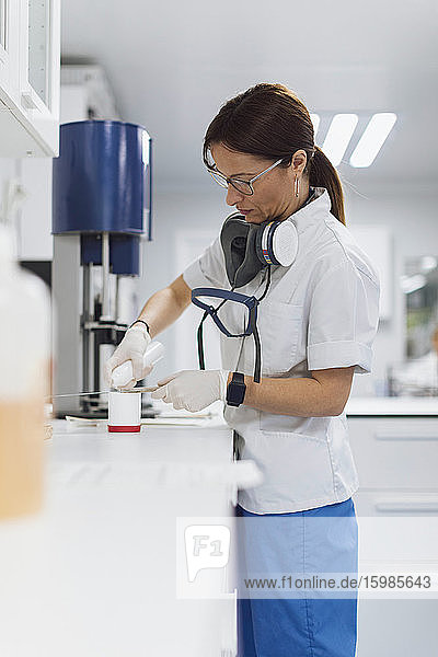 Selbstbewusste Mitarbeiterin des Gesundheitswesens gießt Medikamente in einen Behälter im Labor